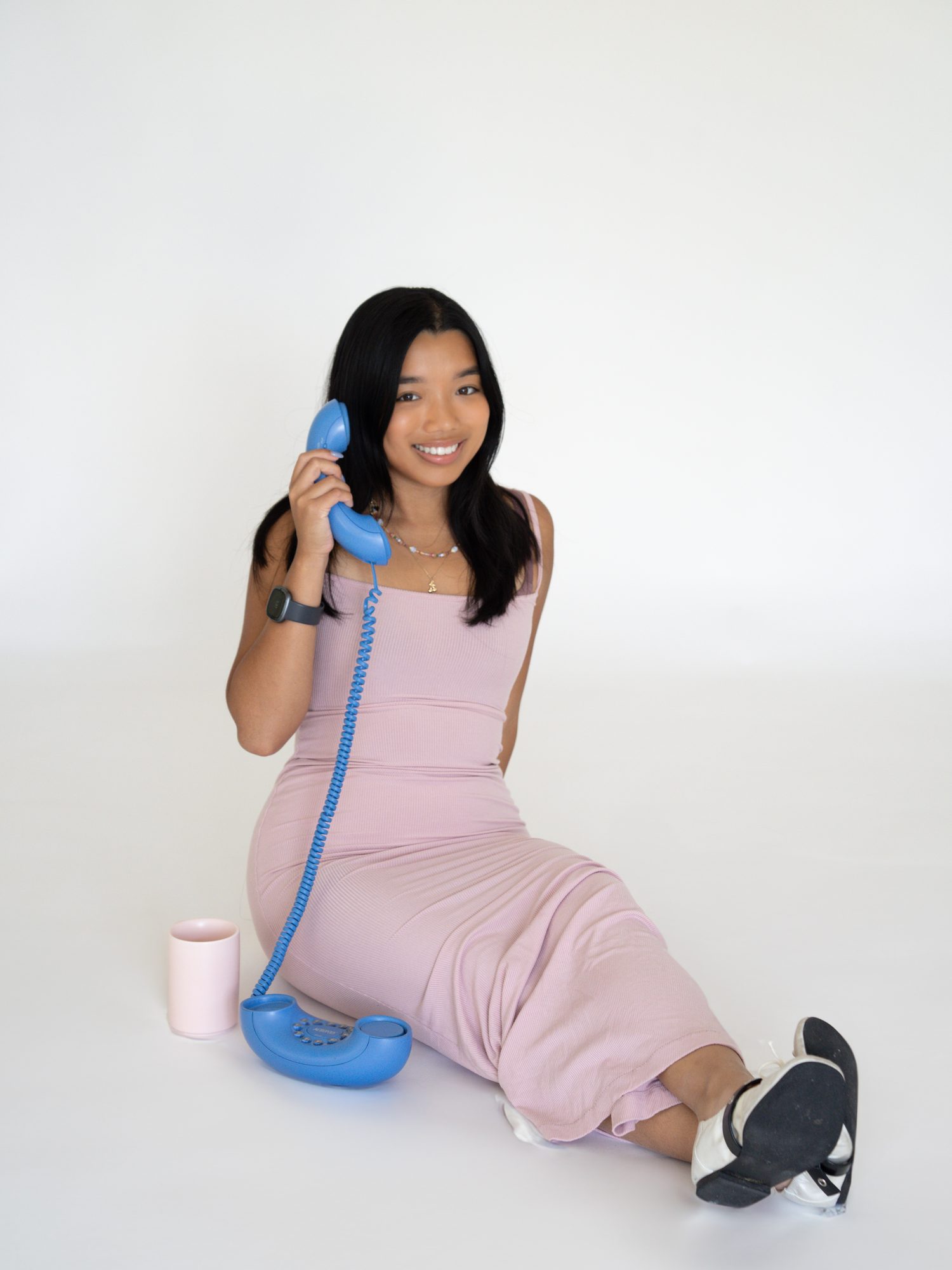 Patricia Redulla smiling on a vintage phone in a pink dress